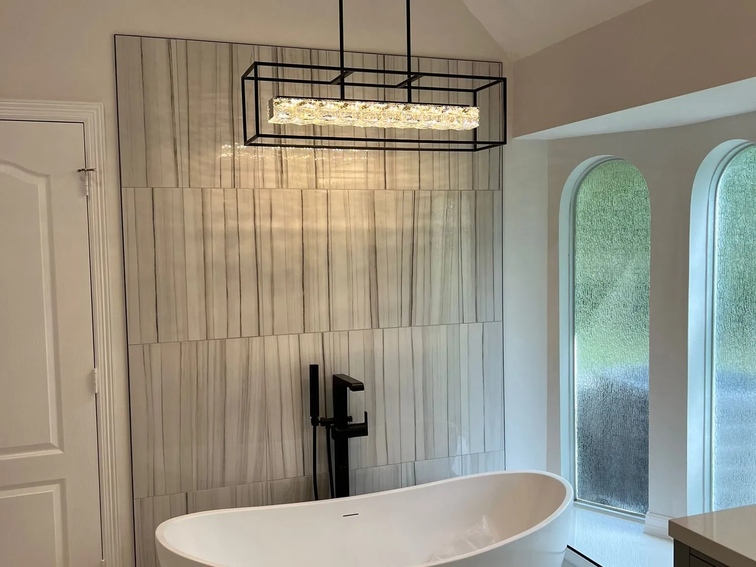 Freestanding tub set beneath arched windows in a primary bathroom remodel in The Woodlands, TX