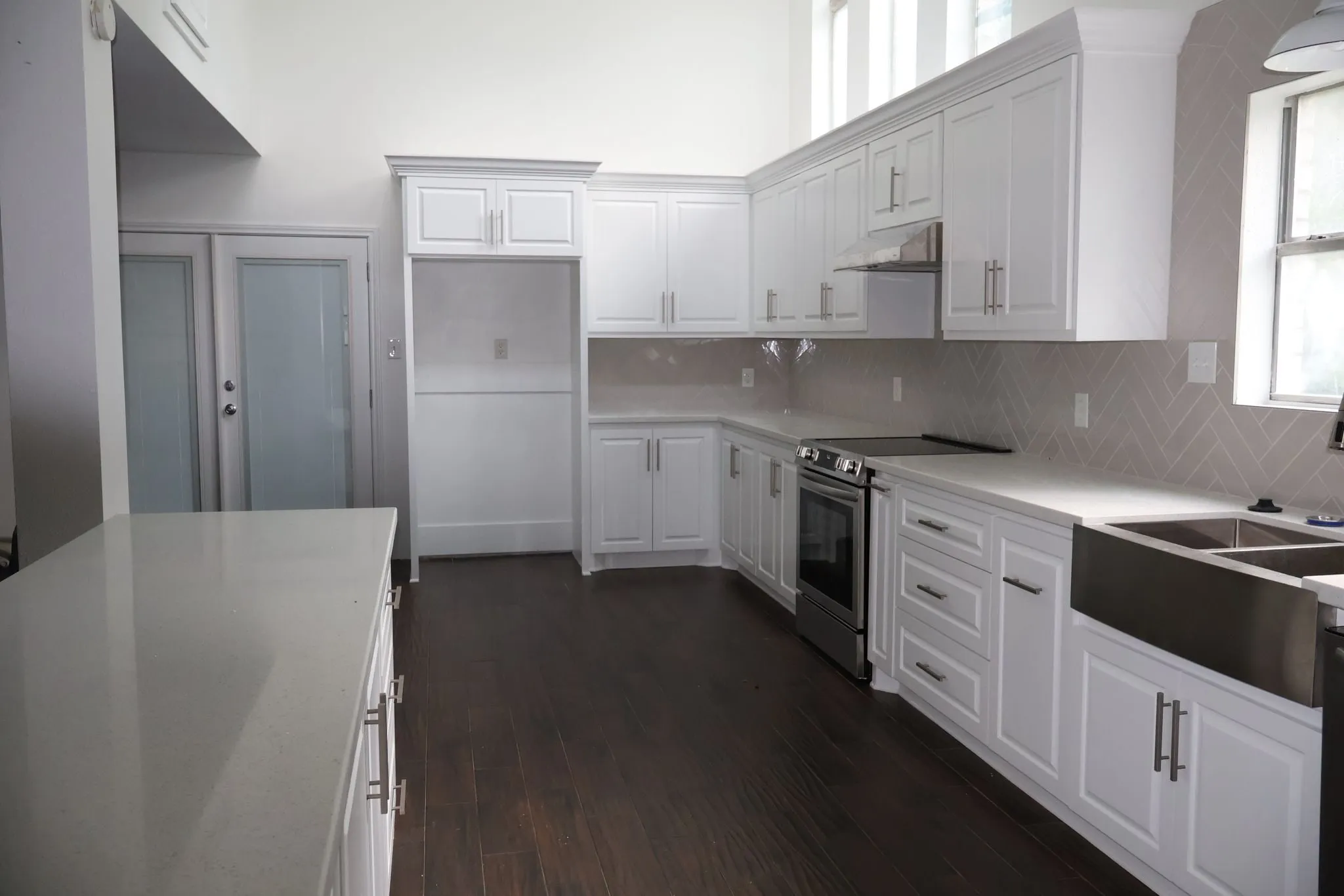 White shaker kitchen remodel with a herringbone backsplash in Panther Creek, The Woodlands, TX