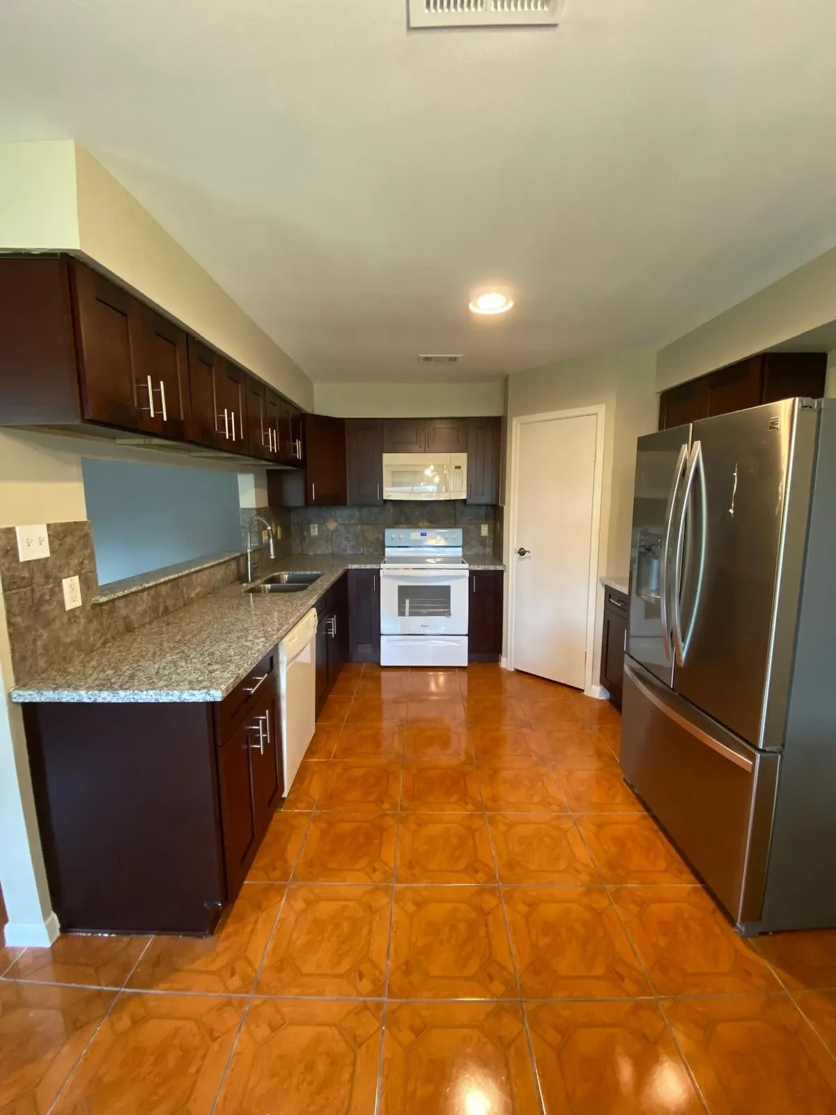 Espresso kitchen cabinetry with granite counters and a stained concrete floor in The Woodlands, TX
